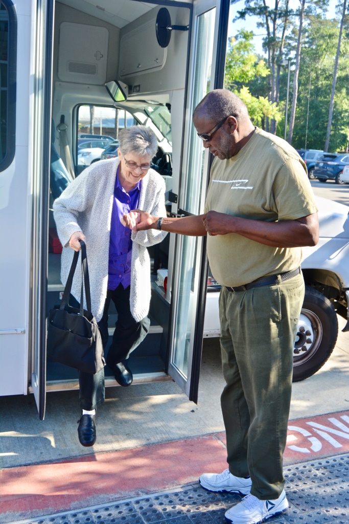 Bus driver helping older female exist the vehicle.