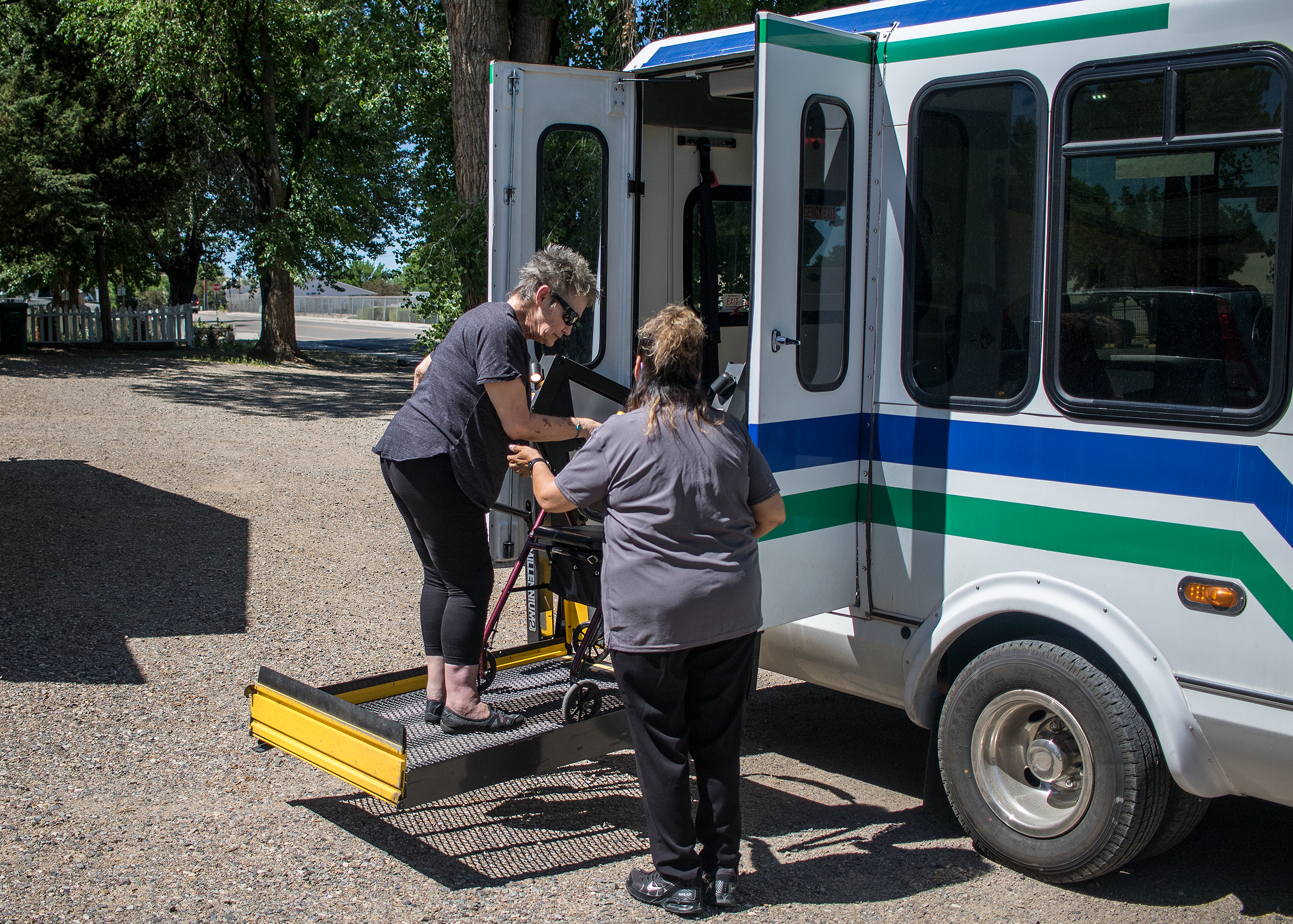 A transit driver assisting a passenger who uses a walker to use the vehicle's lift.