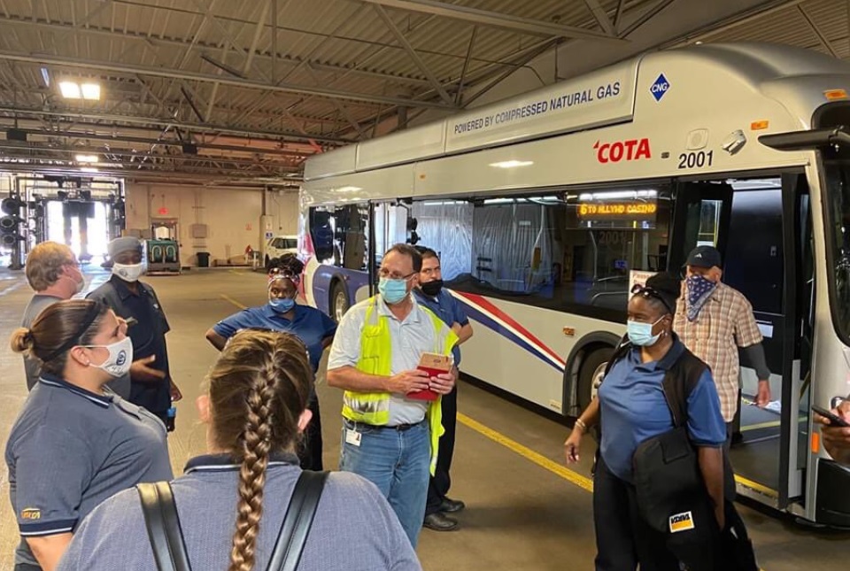 bus drivers standing outside of large bus as part of a training