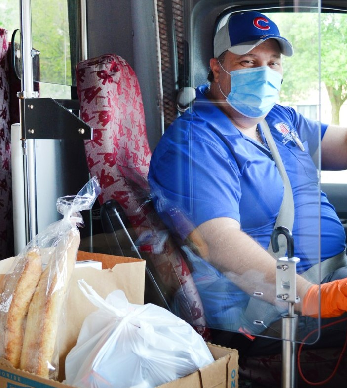 Driver on bus wearing face mask delivering groceries
