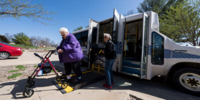 Driver assists woman with walker on bus lift