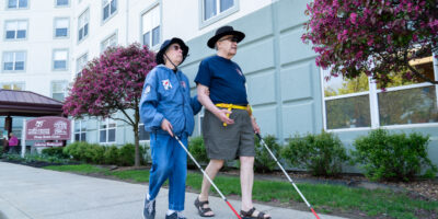 Two older adults walking with white canes