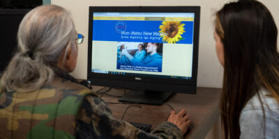 DSC08858 Volunteer assisting gray-haired man with computer