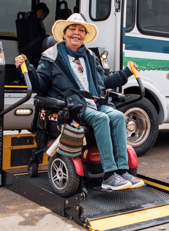 Woman in power wheelchair exiting bus off of lift