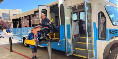 Mountain Ride Bus Driver Driver assisting passenger in wheelchair on lift to exit vehicle