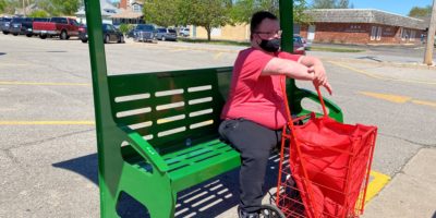 Passenger waiting at bus shelter with shopping cart