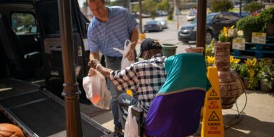 man helps put groceries in vehicle