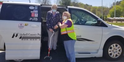 NADTC Photo Gallery Driver assisting older woman with cane off vehicle, both are wearing masks