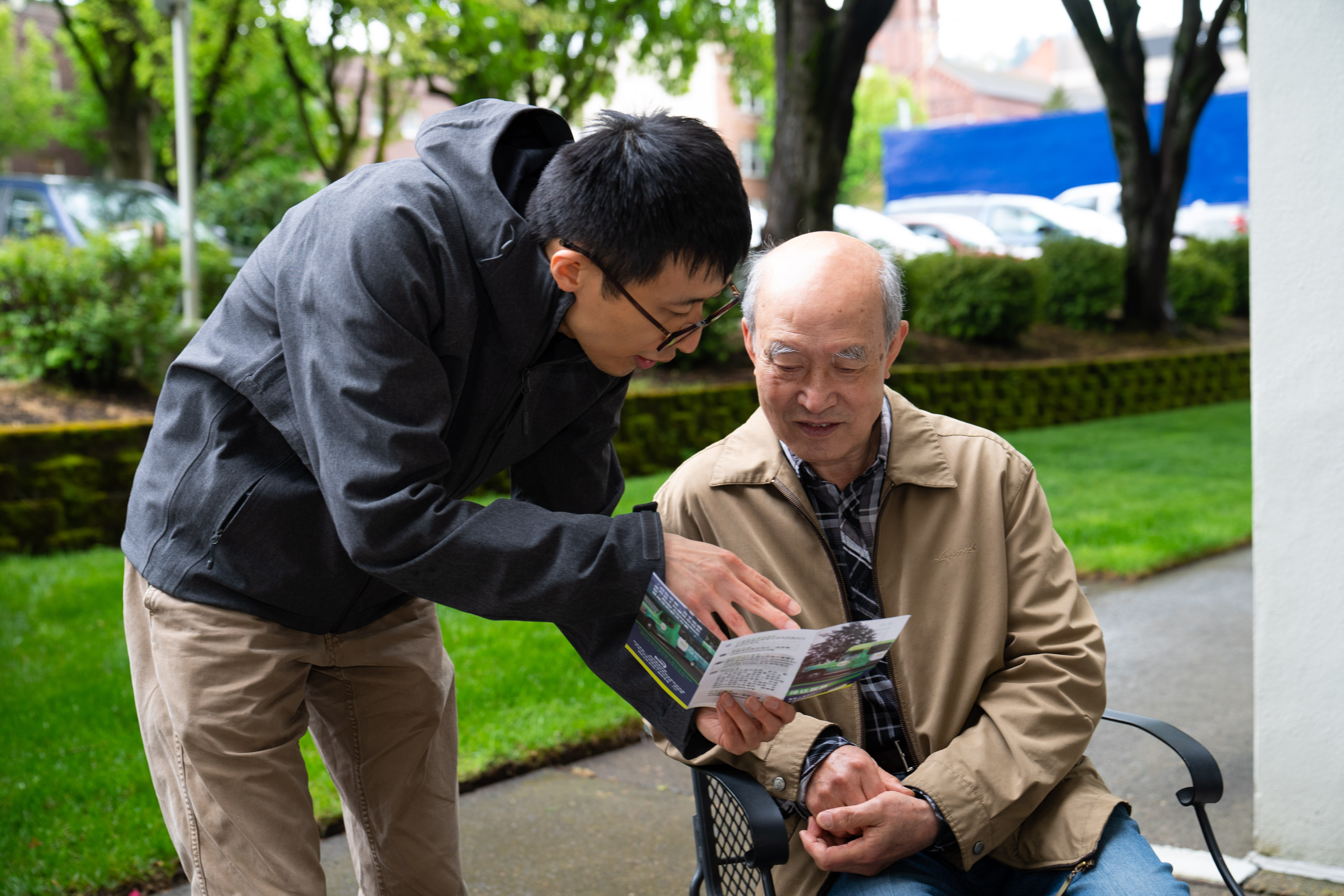 Asian man showing pamphlet to older Asian gentleman