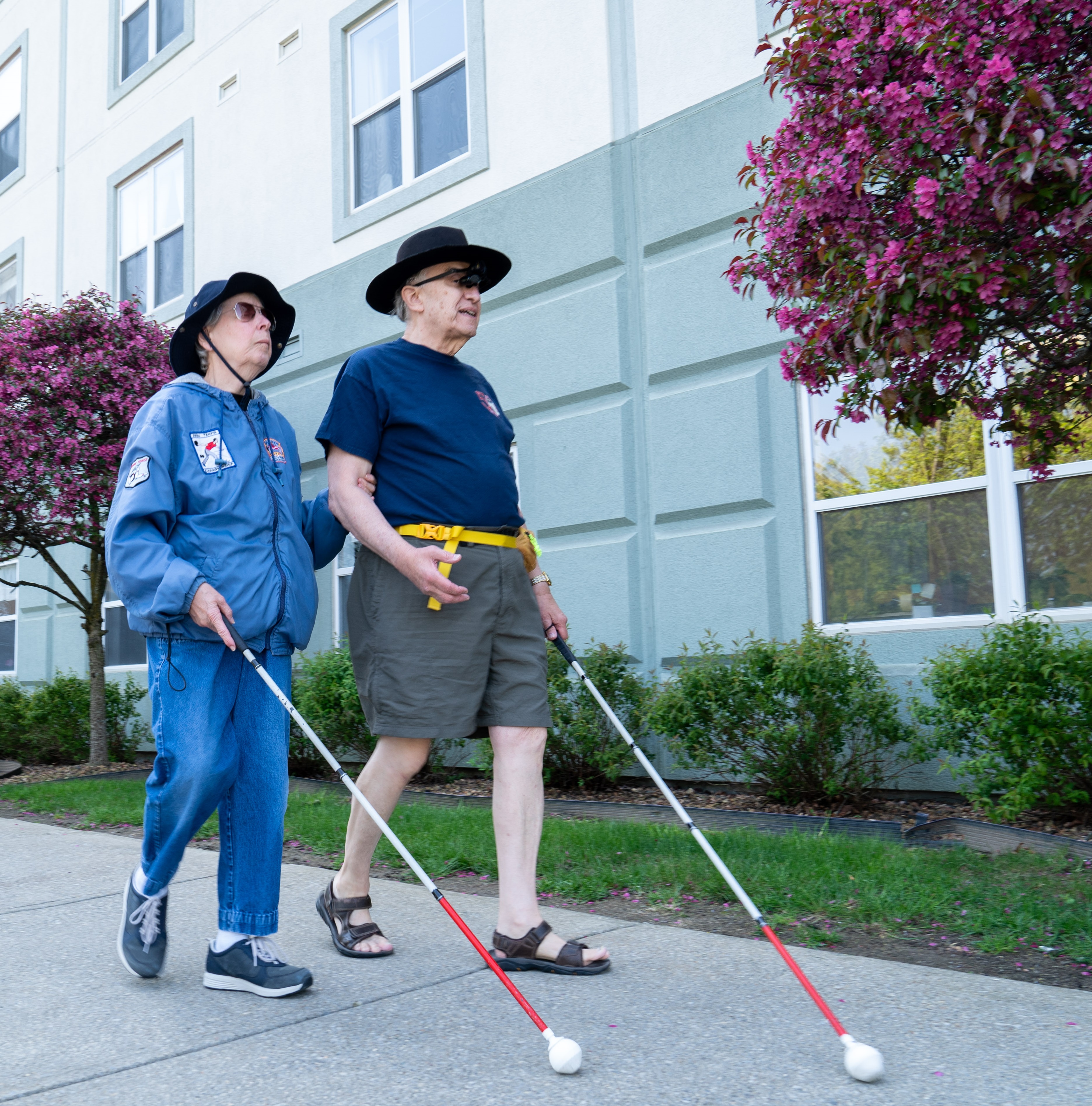 couple walks hand in hand with white canes