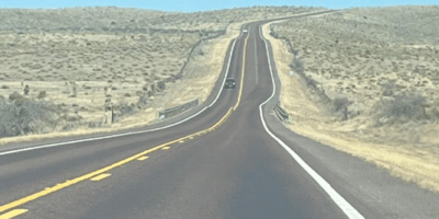A long paved road stretches into the distance in the Texas desert.