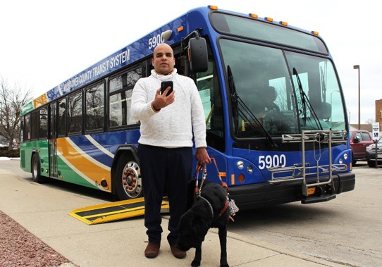 man and guide dog in front of bus