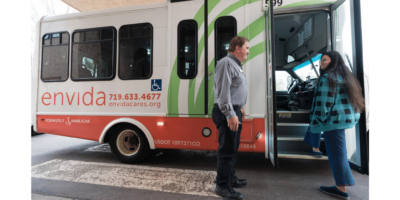 Driver assisting young adult boarding bus