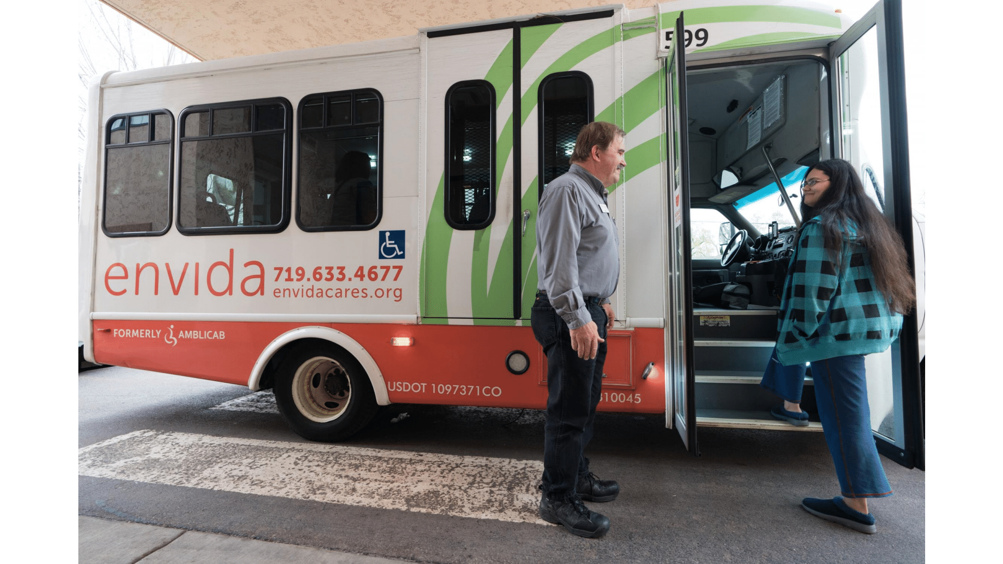 Driver assisting young adult boarding bus