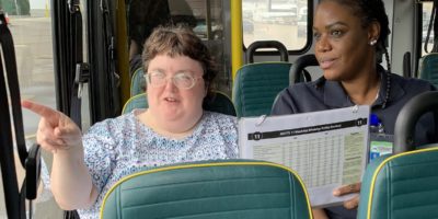 Travel trainer with individual with disability on bus