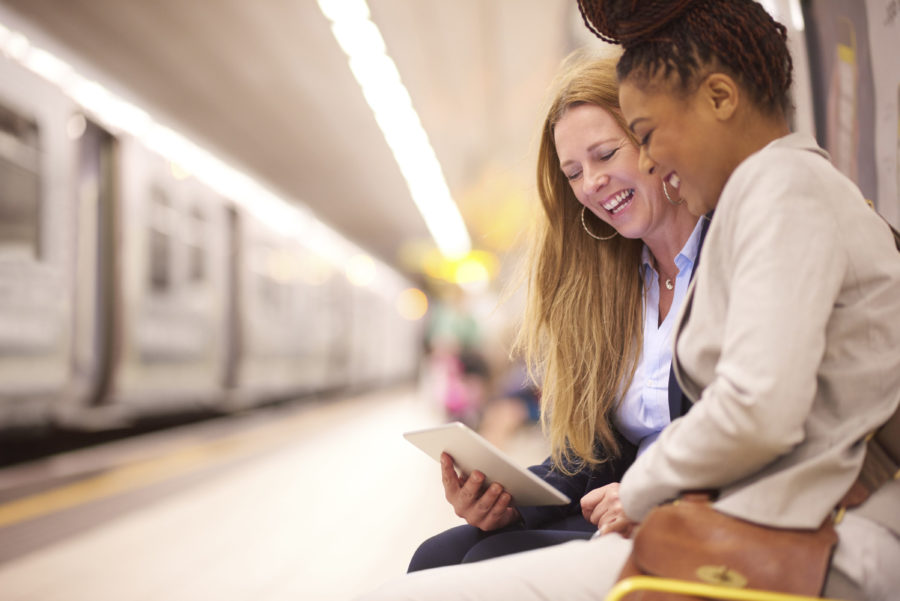 Two women looking at an ipad in a subway station