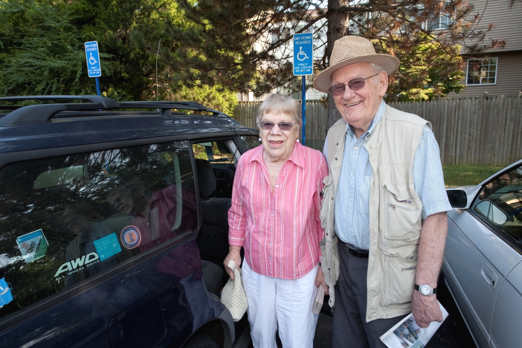 Older man and woman standing next to their car