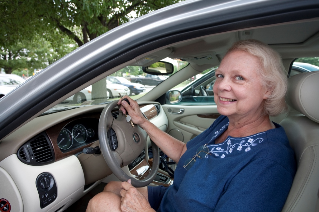 Photo of older woman sitting behind wheel of a car.