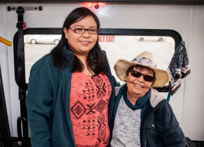Two Native American women, one older and one younger, in the back of a transit van smiling. 