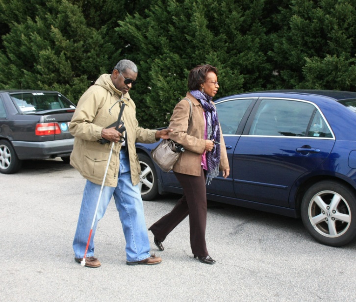 Woman assisting blind man with cane